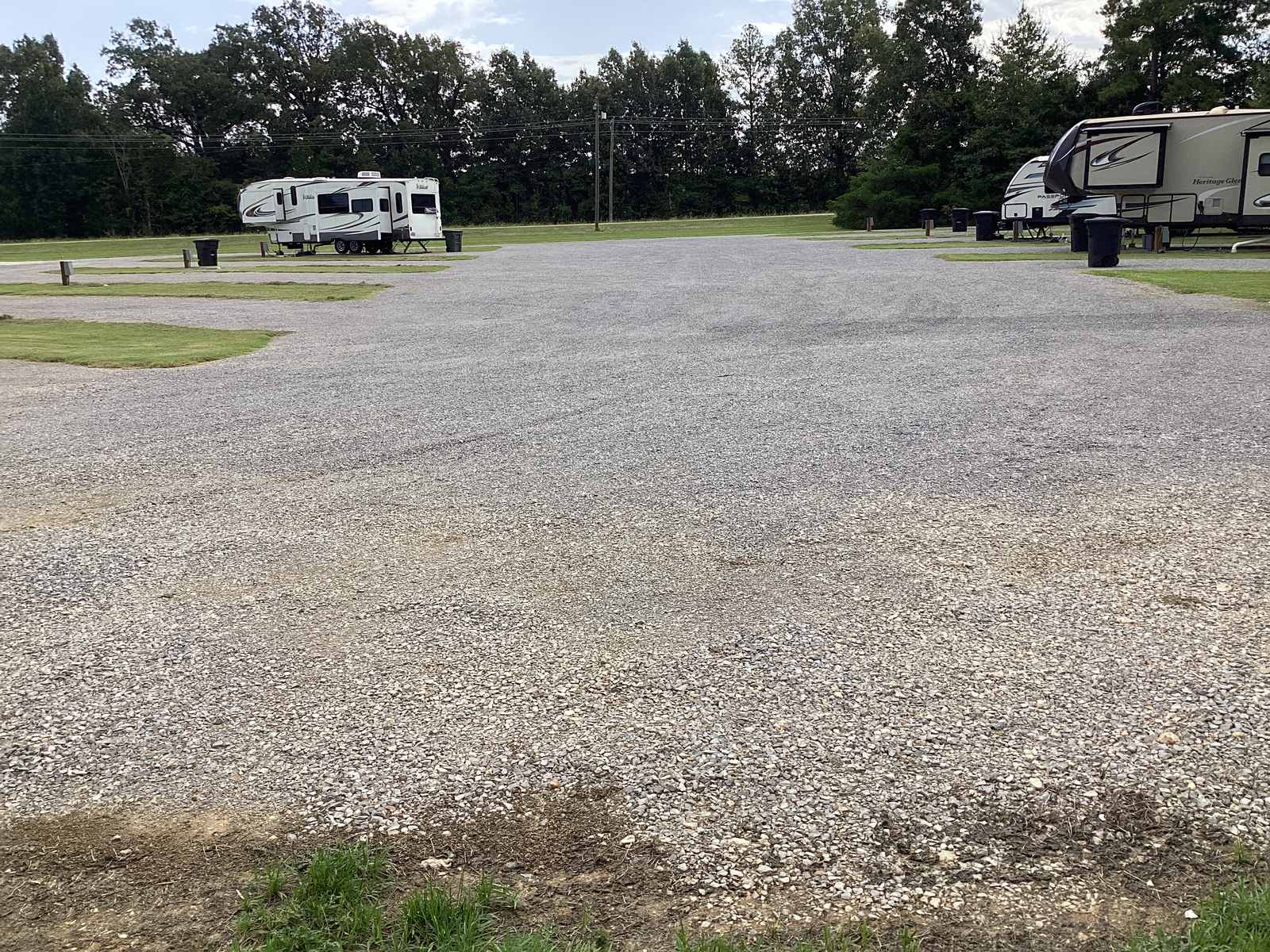The wide gravel drive running between two rows of RVs at Wilbrook RV Park, plenty of room to turn a large RV, trees along the back of the property.